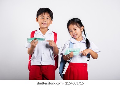 Two Asian Student Kid Girl Boy Brother Sister Wearing Student Thai Uniform Holding Protect Mask Ready To Go To School In Studio Shot Isolated On White Background, New Normal Back To School