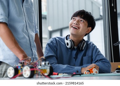 Two Asian Teenagers Constructing Robot Project In Science Classroom. Technology Of Robotics Programing And STEM Education Concept.