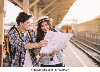 Two Asian Tourists With Backpacks Train Travel In At The Train Station With A Traveler, Vintage Style.