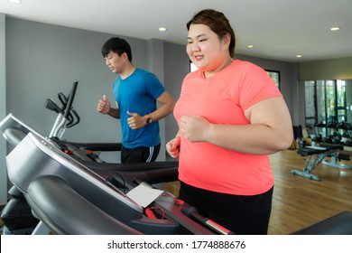 Two Asian trainer man and Overweight woman exercising training on treadmill in gym, trainer thump up to her for good result during workout. Fat women take care of health and want to lose weight.