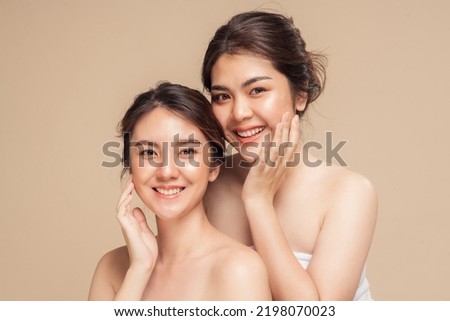 Two Asian woman with beauty face touching healthy skin care. Beautiful female models happy smiling with perfect face skin and natural makeup on beige background. Spa skin care concept.