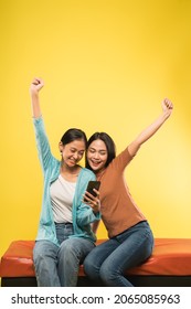 Two Asian Woman Happy With Hands Up When Surprised Looking A Mobile Phone Screen