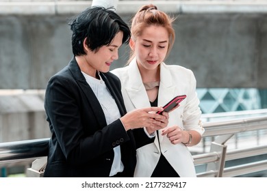 Two Asian Woman Talking Business Partners Using Digital Tablet Smartphone Meeting Outside Office At Street City. Teamwork Partnership Women Talking Discuss At Outdoor Office Partnership Team Advice.