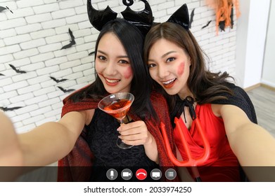 Two Asian Woman Wearing Witch Halloween Costume Talking To Facetime Video Calling In Halloween Party. Videochat Online App With Mic, Video, Phone, Share Screen, Direct Message Icon