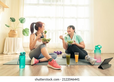 Two Asian Women Body Size Different In Sport Wear Sitting Healthy Eating Vegetable Salad After Exercise At Home Together. Dieting And Exercise At Home Concept.