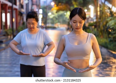 Two asian women doing traditional Chinese Tai Chi, Taiji, Taijiquan meditation in the evening, urban public park environment - Powered by Shutterstock