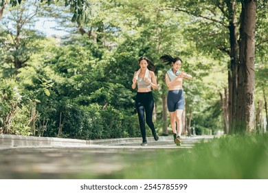 two Asian women engaging in physical activity within an urban park. They are incorporating smart devices to monitor and track their body data using technology. - Powered by Shutterstock