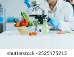 Two Asian women in a lab work on food research, using a microscope, petri dish, and test tubes filled with chemical solutions. They study vegetables, pork, and plants for GMO traits and nutrition.