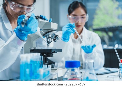 Two Asian women in a lab work on food research, using a microscope, petri dish, and test tubes filled with chemical solutions. They study vegetables, pork, and plants for GMO traits and nutrition.