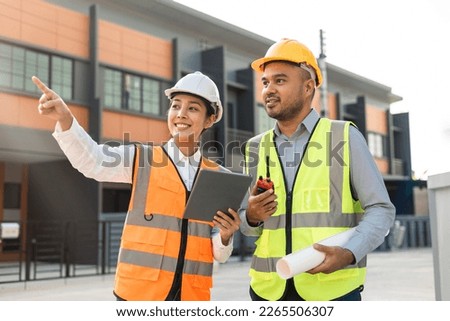 Two Asian worker engineer architect man and woman architect looking construction with white safety helmet in modern home building construction. Work planning with blueprint and tablet. Stock foto © 
