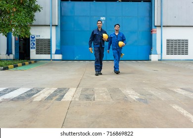 Two Asian Workers Wearing Blue Uniforms While Walking Out From Factory After Work