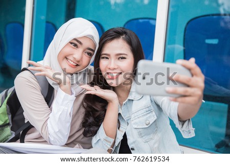 two asian young student taking selfie together with smartphone on campus