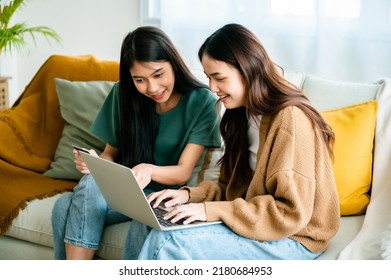 Two asian young woman happy smiling and using computer laptop on couch in living room at home - Powered by Shutterstock