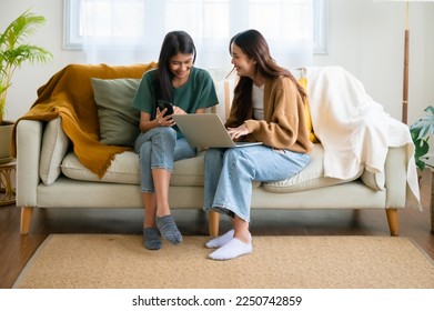 Two asian young woman happy smiling and using computer laptop on couch in living room at home - Powered by Shutterstock