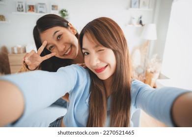 Two asian young women happy smiling and taking selfie in living room at home. Video call, Meeting conference - Powered by Shutterstock