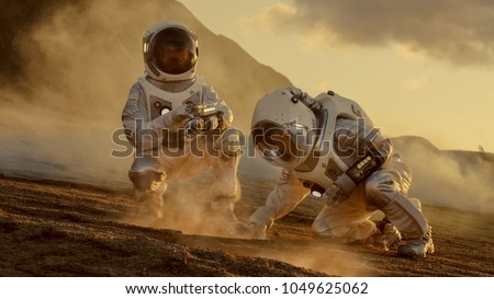 Two Astronauts Collect Soils Samples on Alien Planet, Analyzing Them with Hands Computer. Mars/ Red Planet Manned Expedition.