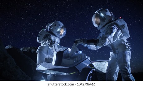 Two Astronauts in Space Suits on an Alien Planet Prepare Space Rover for Surface Exploration Mission. Futuristic Concept about Space Colonization. - Powered by Shutterstock