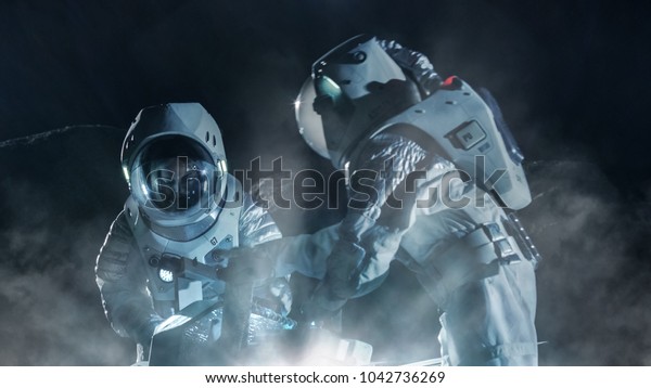 Two Astronauts in Space Suits on\
an Alien Planet Prepare Space Rover for Surface Exploration\
Mission. Futuristic Concept about Space Travel and\
Colonization.