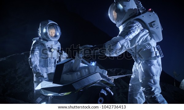 Two Astronauts in Space Suits on an Alien\
Planet Prepare Space Rover for Surface Exploration Mission.\
Futuristic Concept about Space\
Colonization.