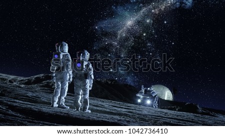 Two Astronauts in Space Suits Stand on the Planet and Looking at the The Milky Way Galaxy. In the Background Lunar Base with Geodesic Dome. Moon Colonization and Space Travel Concept.