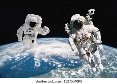 Two astronauts walking in space with earth background. Elements of this image furnished by NASA. - Shutterstock ID 1827604880