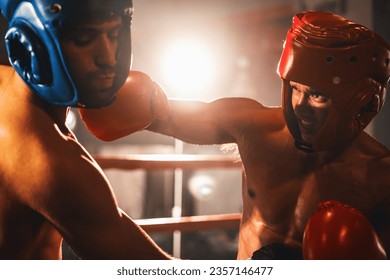 Two athletic and muscular body boxers with safety helmet or boxing head guard face off in fierce boxing match. Boxing fighter competitor fighting in the boxing ring. Impetus - Powered by Shutterstock