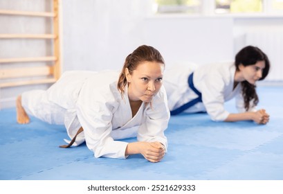 Two athletic women in kimonos doing stretching before karate ore judo training - Powered by Shutterstock