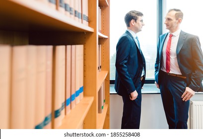 Two Attorneys Discussing Very Interesting Topics In Law Firm Standing In Front Of Book Shelf