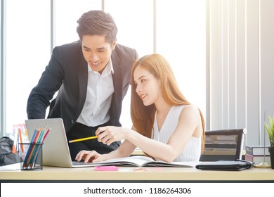 Two Attractive Asian Business People Looking At Laptop Screen.