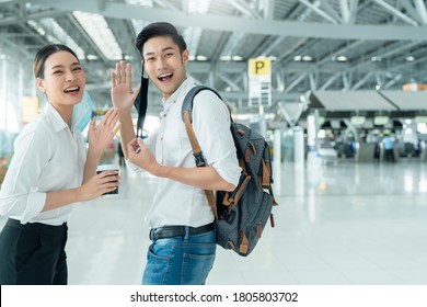 Two Attractive Asian Businessman And Businesswoman Hand Gesture Wave Greeting And Goodbye Social Distancing In Departure Airport Terminal