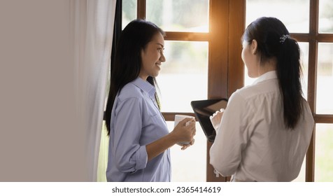 Two attractive Asian women holding a digital tablet and talking with friends at home, Two ideas woman. - Shutterstock ID 2365414619