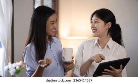 Two attractive Asian women holding a digital tablet and talking with friends at home, Two ideas woman. - Shutterstock ID 2365414639