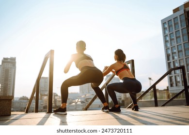 Two attractive female exercising outdoor. Stretching, fitness, sport and healthy lifestyle concept - Powered by Shutterstock