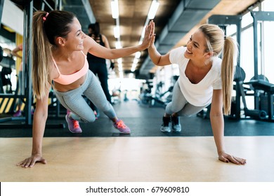 Two attractive fitness girls doing push ups - Shutterstock ID 679609810