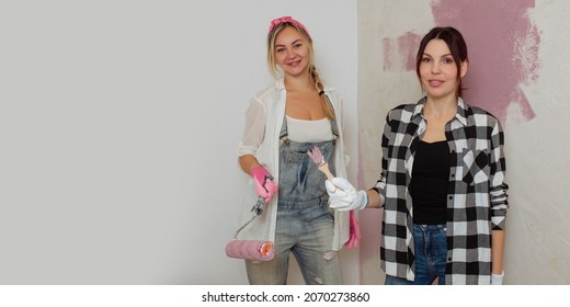 Two Attractive Girlfriends Paint The Wall With A Roller And A Brush. LGBT Family Makes Repairs Inside The House