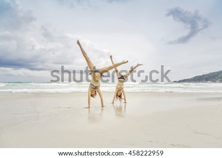 Two Attractive Girls in Bikinis upside down on the Beach. Best Friends Having Fun, Summer Lifestyle.