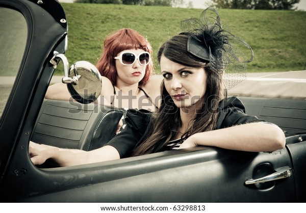 Two\
attractive girls driving around in vintage\
car