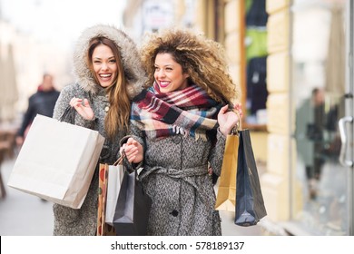 Zwei attraktive lächelnde junge Frauen kaufen in der Stadt ein