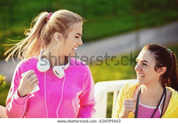 Two attractive and sporty girl friends\
exercising on the bridge. Living healthy\
lifestyle.