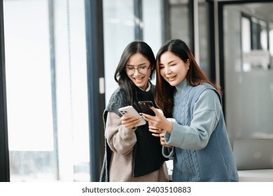 Two Attractive young Asian female college students working on the school project using laptop computer and tablet together, enjoy talking and snacking  - Powered by Shutterstock