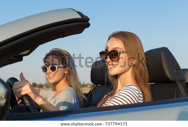 Two attractive\
young women in a cabriolet\
car