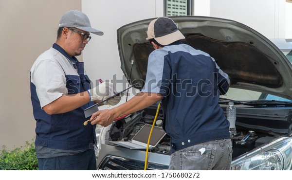 two Auto repairman checks the engine and cooling\
system before traveling on a long holiday. Concept of Car care and\
maintenance from experts, Coaching, and advice For practicing a car\
from an expert