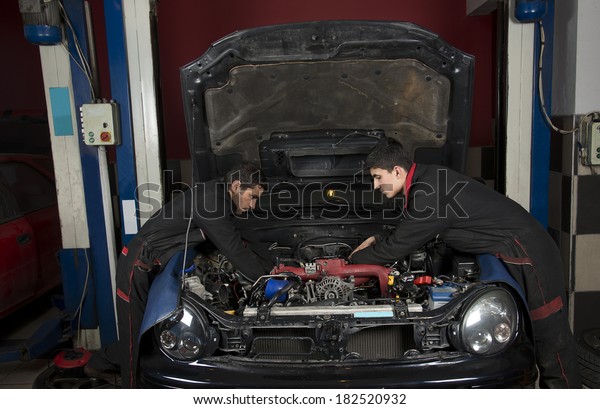 Two auto repairmen fixing a\
car  