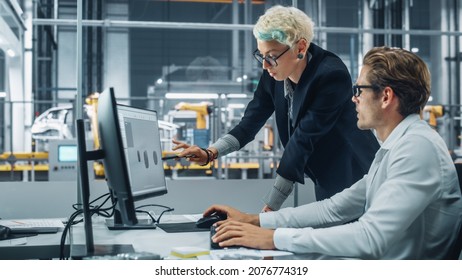 Two Automotive Engineers Discussing Concept Car Blueprints On Desktop Computer In Modern Office At Assembly Plant. Female Industrial Project Manager Talk To Male Designer At Vehicle Factory.