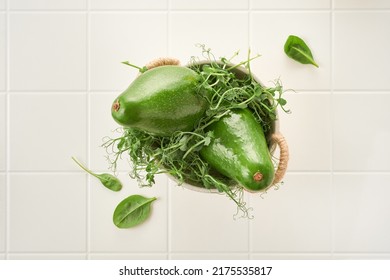 Two Avocado In A Bowl And Pea Sprouts On A White White Kitchen Table. Shallow Depth Of Field. Top View. Selective Focus