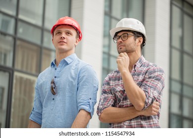 Two Awesome Builders Thinking About The Design Of Construction. Close Up Low Angle Portrait