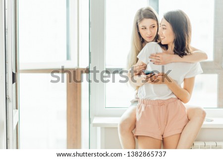 two awesome girls are talking while sending e-mail to a penfriend, close up photo. pleasant conversation, discussion concept