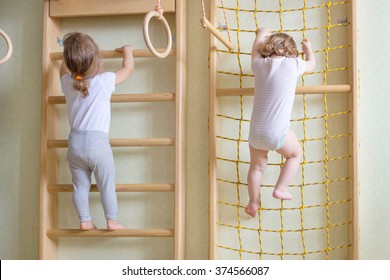 Two Baby Toddlers Climbing Up The Gymnastic Stairs.