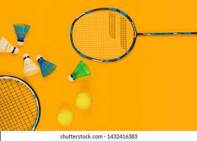 Two Badminton Rackets And Two Shuttlecocks Next To A Jump Rope And Two Tennis Balls On Yellow Background , Shot From Above.