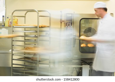 Two bakers working in the kitchen wearing work coats